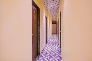 Un corridoio con porte su entrambi i lati, un pavimento decorato e un soffitto con un motivo ripetuto.