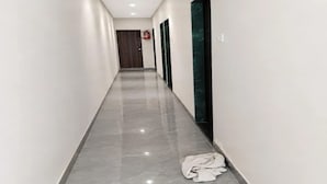 Un pasillo con piso de baldosas brillantes, paredes blancas y una puerta al final.