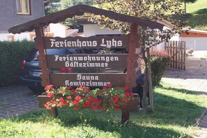 Ein Holzschild mit der Aufschrift, dass hier eine Sauna und Gästezimmer verfügbar sind.