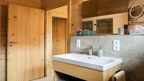 Een houten interieur met een witte wasbak, een spiegel en een handdoekhouder.