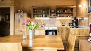 Een houten interieur met een keuken, houten kastjes en een eettafel met een bloemenvaas.
