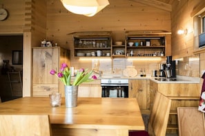 Ein Holzinnenraum mit Küchenzeile, Holzschränken und einem Esstisch mit Blumenvase.