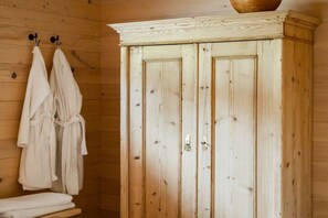Een houten cabin met een houten garderobe, handdoeken aan haken en een houten bank.