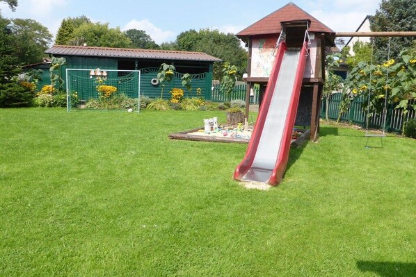 A playground with a slide and a fenced area. - Holiday apartment in Vöhl with swimming pool (Vöhl)