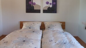 Una camera da letto con un letto matrimoniale, due quadri appesi al muro e una coperta con motivo floreale.