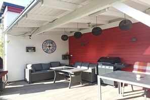 An outdoor patio with a red wall, a barbecue grill, wicker furniture, and a clock on the wall. - Holiday apartment in Vöhl with swimming pool (Vöhl)