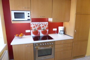 A kitchen with a microwave, stove, oven, and a coffee maker on the countertop. - Holiday apartment in Vöhl with swimming pool (Vöhl)