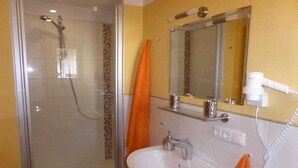 Un bagno con doccia vetro-ceramica, lavandino e specchio.