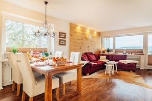 A modern living room with a wooden dining table, white chairs, a red sofa, and a leather couch. - Holiday apartment with 1 bedroom (Braunlage)