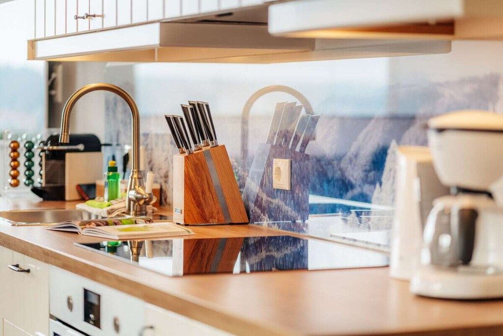 Een keuken met een modern design, voorzien van een roestvrijstalen spoelbak, een koffieapparaat en een messenblok.