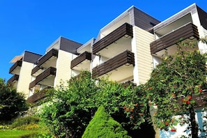 A modern multi-story building with balconies and a well-maintained garden. - Holiday apartment with 1 bedroom (Braunlage)