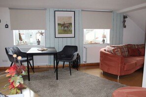 A living room with a dining table, two chairs, a sofa, and a radiator. - Bremmer Hof " Stubenblick" (Bremm)