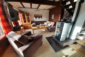 Ein Wohnzimmer mit einer Couch, einem Couchtisch, einem Kamin und einem Fernseher.