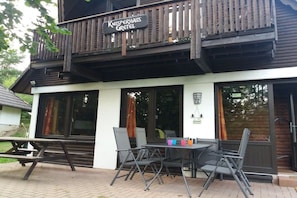 Ein Holzhaus mit Balkon und Tisch mit Stühlen vor der Fassade.