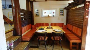 A dining area with a wooden table and striped cushioned benches. - Gingerbread House Gretel (Frankenau)