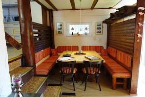 A dining area with a wooden table and striped cushioned benches. - Gingerbread House Gretel (Frankenau)