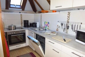 A compact kitchen with a built-in oven, dishwasher, and a coffee maker. - Gingerbread House Gretel (Frankenau)