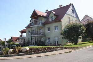 Ein mehrstöckiges Gebäude mit einem Balkon, einer Steinmauer und einem gepflegten Rasen.