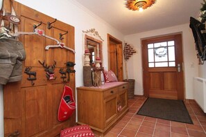 Ein Holzflur mit Kleiderhaken, einem Spiegel und einer Tür mit Fenster.