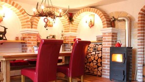 A cozy dining area with a brick fireplace, red chairs, and a table with various items. - Holiday apartment with 2 bedrooms (Tittmoning\/Törring)