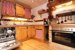 A kitchen with wooden cabinets, a dishwasher, a stove, and hanging pots. - Holiday apartment with 2 bedrooms (Tittmoning\/Törring)