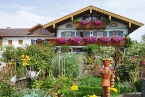 Ein traditionelles Chalet mit einem Balkon, der mit Blumen geschmückt ist, umgeben von einem üppigen Garten.