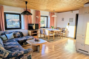 A cozy living area with a sofa, a TV, a dining table with chairs, and a kitchen area with cabinets. - Holiday apartment with 1 bedroom (Lohberg)