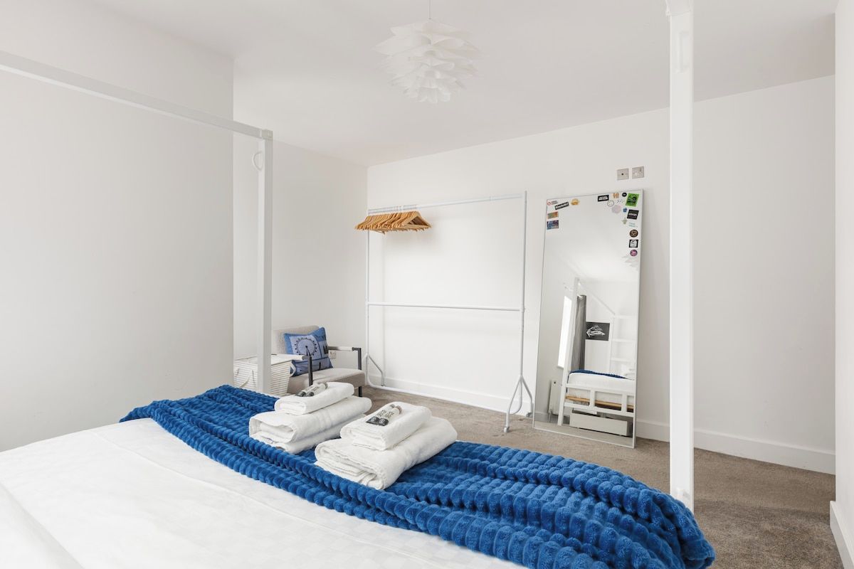 A modern bedroom with a bed, a wardrobe, a mirror, and a hanging rack.