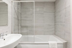 Ein modernes Badezimmer mit einer gläsernen Dusche, einer weißen Badewanne und einem Waschbecken.