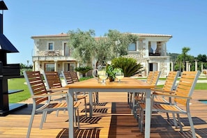 A wooden deck with a table and chairs, a stone building in the background, and a clear sky. - Ses Rentedores [2257] (Selva)
