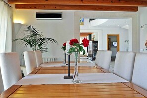 En matplats med ett träbord, vita stolar och en vas med röda blommor.