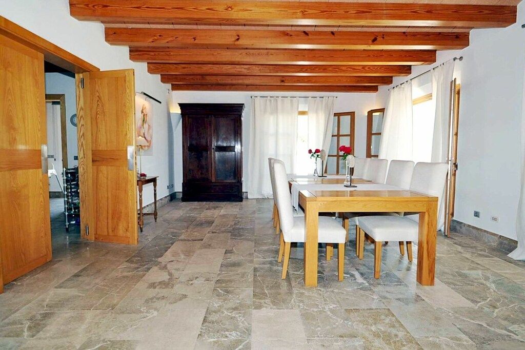 Ein Essbereich mit Holztisch und -stühlen, Steinboden und Holzbalkendecke.