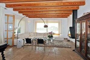 A living room with a wooden ceiling, a sofa, a coffee table, and a television. - Ses Rentedores [2257] (Selva)
