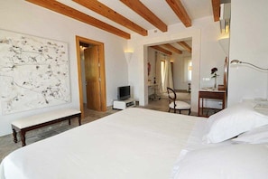 A bedroom with a large bed, a TV, a bench, and a painting on the wall. - Ses Rentedores [2257] (Selva)