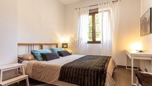 A bedroom with a bed, bedside table, lamp, and a window with curtains. - SaTorre Voramar [4501A] (Sa Torre)