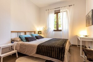 A bedroom with a bed, bedside table, lamp, and a window with curtains. - SaTorre Voramar [4501A] (Sa Torre)