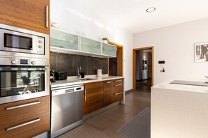 A modern kitchen with built-in appliances, wooden cabinets, and a glass-fronted upper cabinet. - SaTorre Voramar [4501A] (Sa Torre)