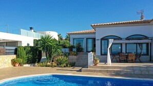 A residential property with a swimming pool, a patio with outdoor furniture, and a modern house with large windows. - SaTorre Voramar [4501A] (Sa Torre)