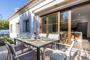 An outdoor dining area with a table set for four, overlooking a body of water. - SaTorre Voramar [4501A] (Sa Torre)