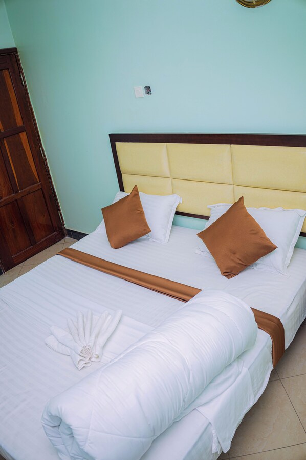 A neatly made bed with white linens, two brown pillows, and a decorative towel.