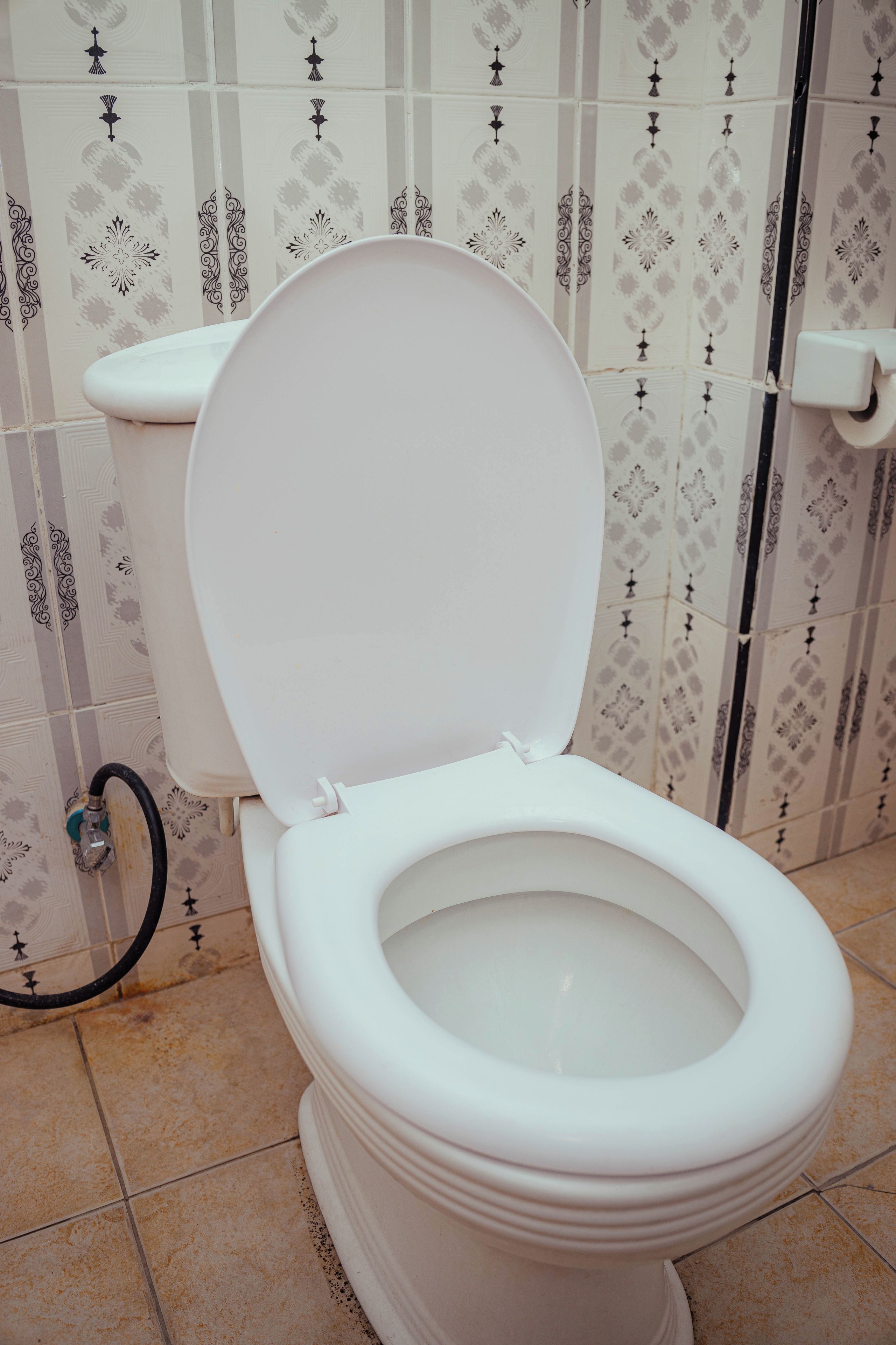 Un inodoro blanco con la tapa cerrada en un baño con baldosas estampadas.