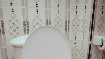 Un inodoro blanco con la tapa cerrada en un baño con baldosas estampadas.