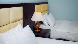 Une chambre d’hôtel avec deux lits simples, une table de chevet avec une lampe et un interrupteur fixé au mur.