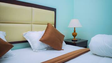 A neatly made bed with a headboard, a bedside lamp, and pillows.