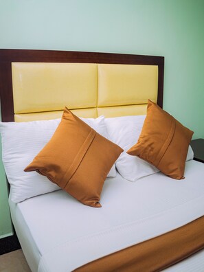 A bed with a headboard, two pillows, and a white bedspread.