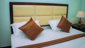 Un lit avec une tête de lit, deux oreillers, une table de chevet avec une lampe et une commode.