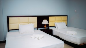 Une chambre d’hôtel avec deux lits, chacun doté d’une tête de lit, de draps blancs et d’une table de chevet avec une lampe.