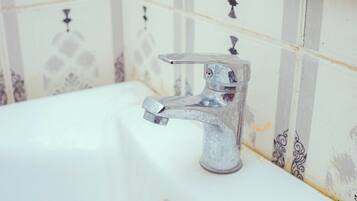 A bathroom with a white sink, a faucet, and patterned tiles on the wall.