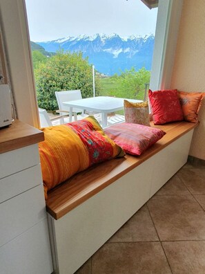 Quarto com assento embutido e vista para uma paisagem montanhosa.