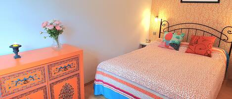 A bedroom with a bed, a dresser, a nightstand, a wall-mounted picture, and a window.
